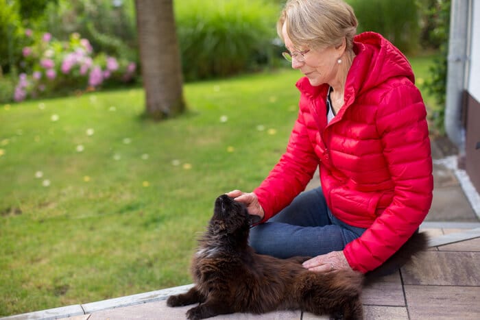 Eine Person mit besorgtem Gesichtsausdruck sucht im Freien, wahrscheinlich nach einer verlorenen Katze.