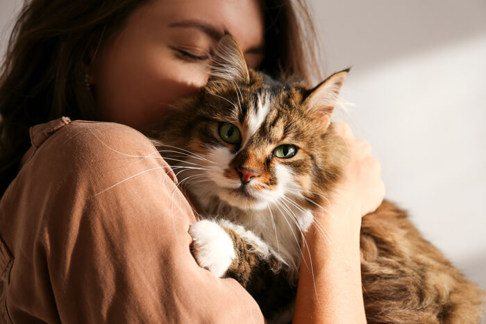 Frau hält und umarmt zärtlich ihre geliebte Katze