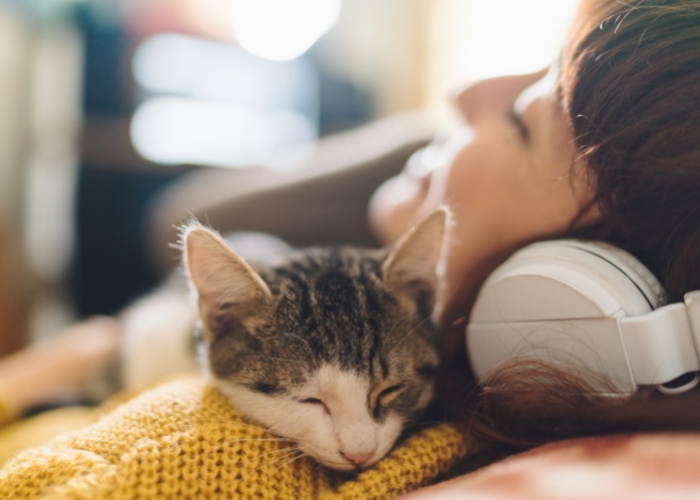 Bild, das eine Frau und ihre Katze zeigt, die gemeinsam Musik hören.