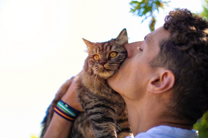 Mann im Garten umarmt und küsst eine Katze